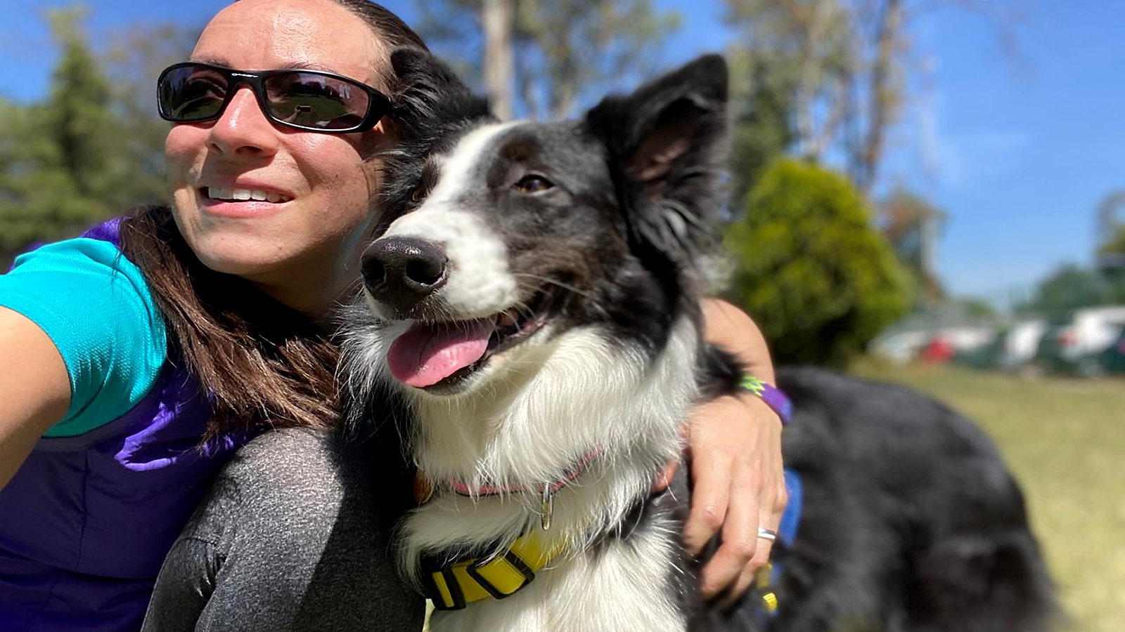 La Dra. Gina Rumbos abrazando a un border collie en un parque